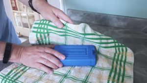 person wrapping ice-block in tea towel