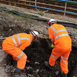 two rail workers digging